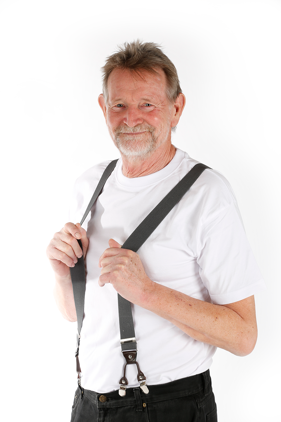 Helbredstjek 70 år: Portræt af en mand i hans 70'ere, der står iført en hvid T-shirt og sorte bukser med seler. Han smiler mod kameraet.